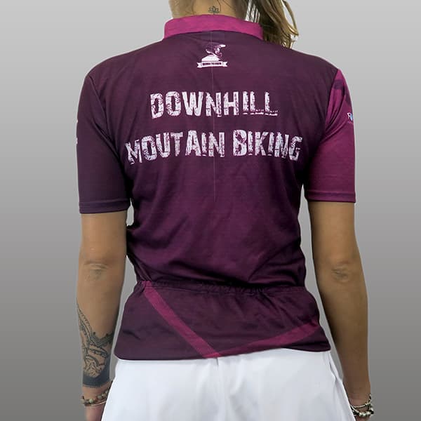 femme de dos portant un maillot de cyclisme violet et rose