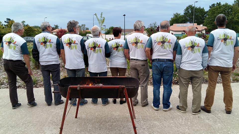 groupe d'hommes portant le même t-shirt debout derrière un barbecue