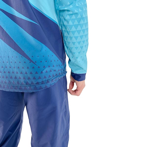 back of a person wearing a sublimated turquoise jacket and blue trousers