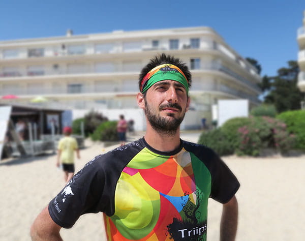 thumbnail man wearing a green and orange headband and colorful jersey at the beach