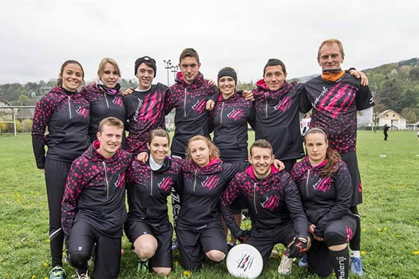 team posing on grass field wearing black and pink sublimated hoodies