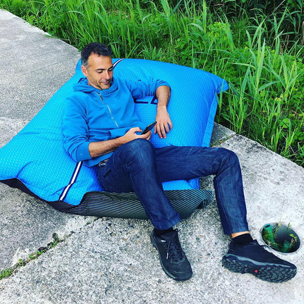 homme assis sur un coussin géant bleu en regardant son téléphone