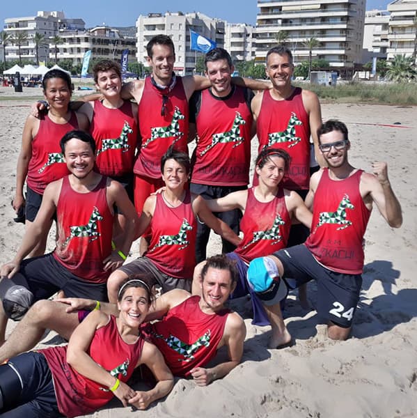 sport team posing on beach wearing red singlets