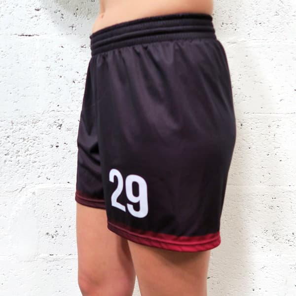 side left view of woman lower body wearing feminine black shorts in front of a white wall