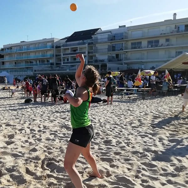thumbnail side view of woman on beach playing spikeball