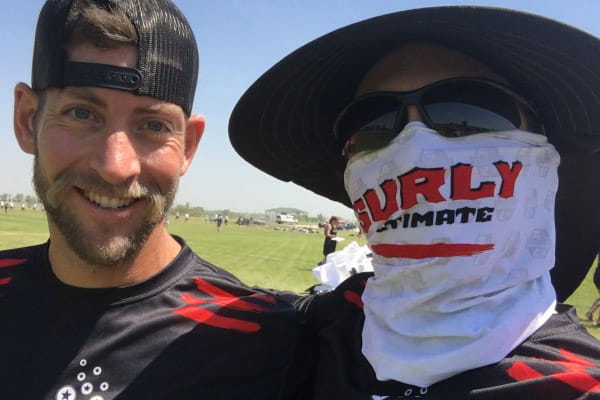 deux hommes l'un souriant l'autre avec des lunettes se cachant derrière un snood blanc