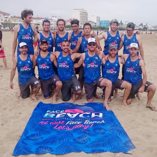 équipe de sport posant sur la plage devant une serviette bleue