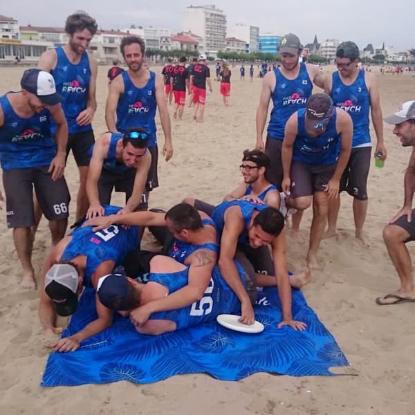 équipe de sport sur la plage tombant sur une serviette bleue